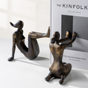 Escultura decorativa abstrata para estantes e mesas, com design moderno e acabamento bronze sofisticado.