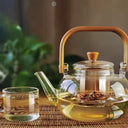 Chaleira de vidro 1L com infusor e alça de bambu natural, servida com chá em ambiente aconchegante - Casa Splêndida