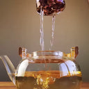 Chaleira de vidro 1L com infusor e alça de bambu natural, servida com chá em ambiente aconchegante - Casa Splêndida