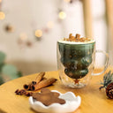 Caneca de Natal Casa Splendida de vidro transparente com detalhes natalinos, servindo chocolate quente com marshmallows.