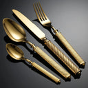 Talheres dourados do Faqueiro Royale Luxo em disposição elegante e iluminação dramática.