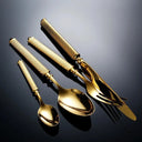 Talheres dourados do Faqueiro Royale Luxo em disposição elegante e iluminação dramática.