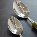 Detalhe das colheres inox 304 com brilho espelhado e cabos bambu, utensílios de mesa refinados.