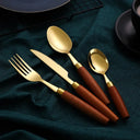 Faqueiro prateado com cabos de madeira exposto elegantemente sobre guardanapo verde em fundo cinza.