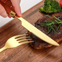 Pessoa utilizando faca dourada com cabo de madeira para cortar carne em tábua de madeira, demonstrando precisão e elegância.
