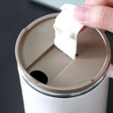 Canecas térmicas com design moderno em branco e bege, ideais para café ou cappuccino, com tampa e alça ergonômica