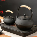 Chaleira japonesa preta de ferro fundido Casa Splendida servindo chá em xícara combinando sobre mesa rústica