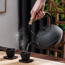Chaleira japonesa preta de ferro fundido Casa Splendida servindo chá em xícara combinando sobre mesa rústica