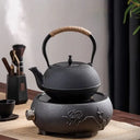Chaleira japonesa preta de ferro fundido Casa Splendida servindo chá em xícara combinando sobre mesa rústica