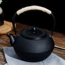 Chaleira japonesa preta de ferro fundido Casa Splendida servindo chá em xícara combinando sobre mesa rústica