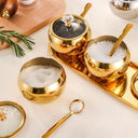 conjunto dourado com 3 potes de inox, tampas de vidro e colheres sobre bandeja – Casa Splendida