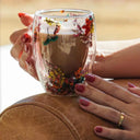 Caneca de vidro duplo com flores secas coloridas e bebida quente sendo servida - Casa Splêndida