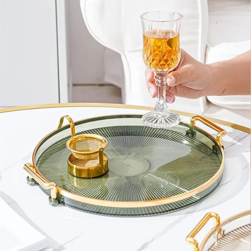 Bandeja acrílica redonda com alça dourada, disponível em verde, âmbar, cinza e transparente, para decoração e organização Casa Splendida.