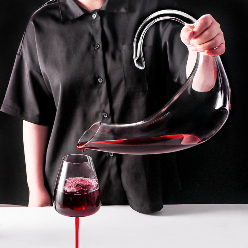 Decanter de cristal com copos para vinho, em mesa sofisticada. Ideal para servir e decorar com elegância.
