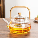 Chaleira de vidro 1L com infusor e alça de bambu natural, servida com chá em ambiente aconchegante - Casa Splêndida