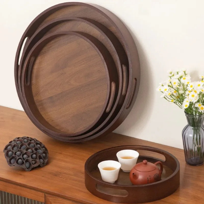 Bandeja de madeira e bambu, formatos redondo e retangular, com alças vazadas laterais, sobre mesa de madeira clara