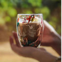 Caneca de vidro duplo com flores secas coloridas e bebida quente sendo servida - Casa Splêndida