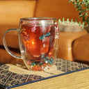 Caneca de vidro duplo com flores secas coloridas e bebida quente sendo servida - Casa Splêndida