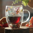 Caneca de vidro duplo com flores secas coloridas e bebida quente sendo servida - Casa Splêndida