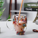 Caneca de vidro duplo com flores secas coloridas e bebida quente sendo servida - Casa Splêndida
