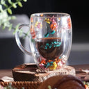 Caneca de vidro duplo com flores secas coloridas e bebida quente sendo servida - Casa Splêndida