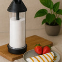 Tapioqueira preta com polvilhador embutido ao lado de panqueca com morangos – utensílio prático para preparo de tapioca sem sujeira.