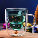 Caneca de Natal Casa Splendida em vidro borossilicato de parede dupla, com bebida quente e decoração natalina ao fundo.