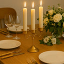 Mesa posta refinada com candelabro dourado, velas altas e arranjo floral branco, decoração Casa Splendida.