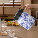 Garrafa térmica azul floral servindo bebida em copos, detalhe do bico ao despejar