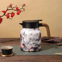 Garrafa térmica estampada marmorizada com tampa preta e alça amadeirada, em ambiente de mesa