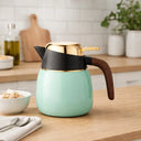 Garrafa térmica verde menta com alça de madeira e tampa dourada em bancada de cozinha, para café e chá