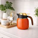 Garrafa Térmica Luxo Valenza para Café e Chá 1L Laranja Casa Splendida sob uma bancada branca ao lado de acessórios para café