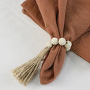 Porta-guardanapo artesanal com contas de madeira natural e tassel de juta – estilo boho e rústico para mesa posta elegante.

