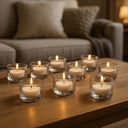 Castiçais de vidro baixo com velas acesas em mesa de centro, destacando decoração minimalista e ambiente confortável.