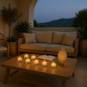 Castiçais de vidro com velas acesas em área externa, criando clima acolhedor e sofisticado ao entardecer.