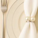 Detalhe do anel para guardanapo com pérolas duplas em acabamento metálico, aplicado em guardanapo claro