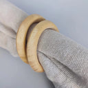 Detalhe do anel de guardanapo em madeira natural em guardanapo cinza, acabamento minimalista para mesa posta