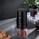 Moedor de café elétrico portátil preto com botão liga/desliga e copo transparente para café moído