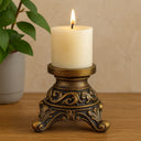 Castiçal dourados estilo europeu com acabamento vintage, decorados com vela alta sobre mesa clássica.