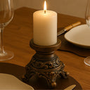 Castiçal dourado estilo europeu com acabamento vintage, decorados com vela alta sobre mesa clássica.