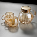 Bule de vidro transparente com tampa dourada e infusor interno, ideal para chás e infusões, sobre mesa de madeira