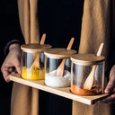 kit com três potes de vidro com tampas e colheres de bambu sobre bandeja