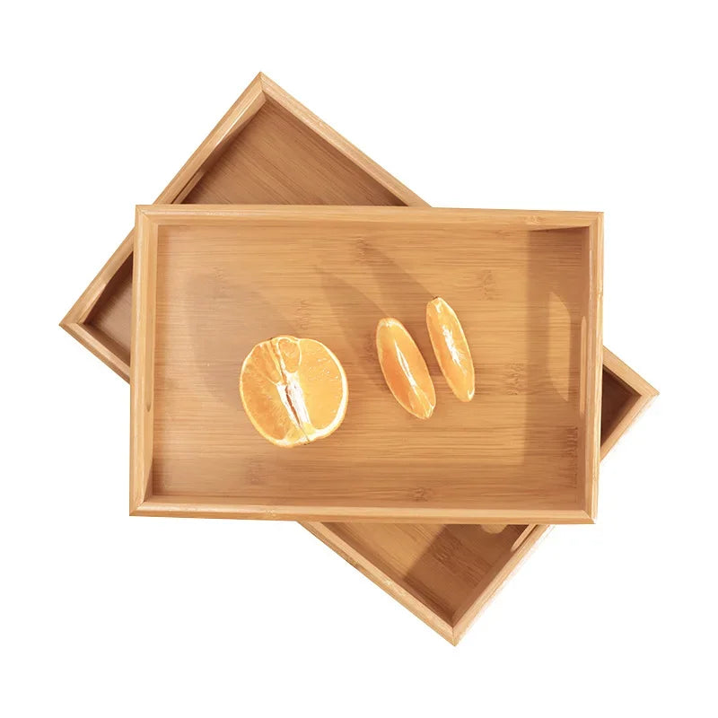 Bandeja retangular de bambu natural com alças vazadas laterais sobre mesa de madeira, ideal para servir e organizar

