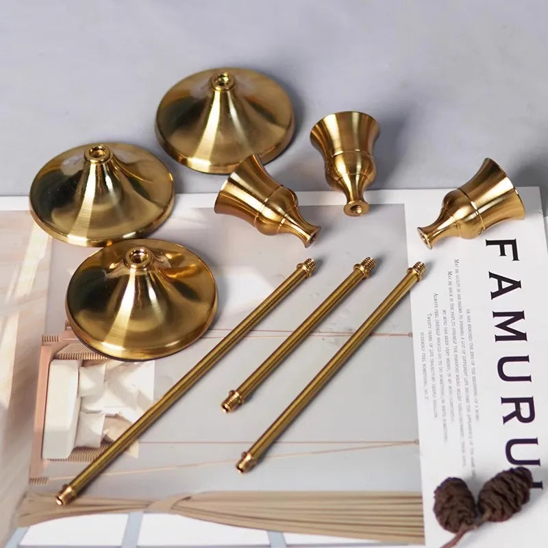 Kit 3 castiçais vintage dourados em alturas diferentes sobre mesa decorada”