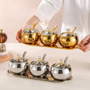 conjunto dourado com 3 potes de inox, tampas de vidro e colheres sobre bandeja – Casa Splendida