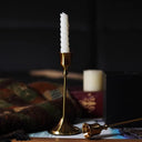 Kit 3 castiçais vintage dourados em alturas diferentes sobre mesa decorada”