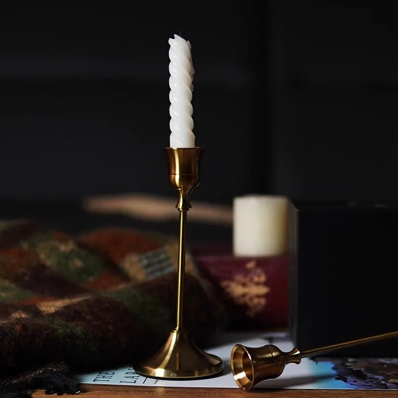 Kit 3 castiçais vintage dourados em alturas diferentes sobre mesa decorada”