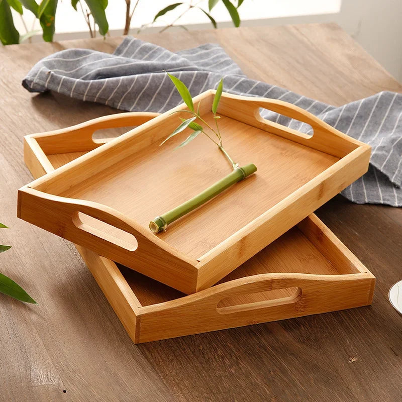 Bandeja retangular de bambu natural com alças vazadas laterais sobre mesa de madeira, ideal para servir e organizar

