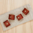 Porta‑guardanapo de couro marrom com rebite metálico em mesa posta estilo farmhouse, conjunto com guardanapos claros