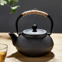 Chaleira japonesa preta de ferro fundido Casa Splendida servindo chá em xícara combinando sobre mesa rústica